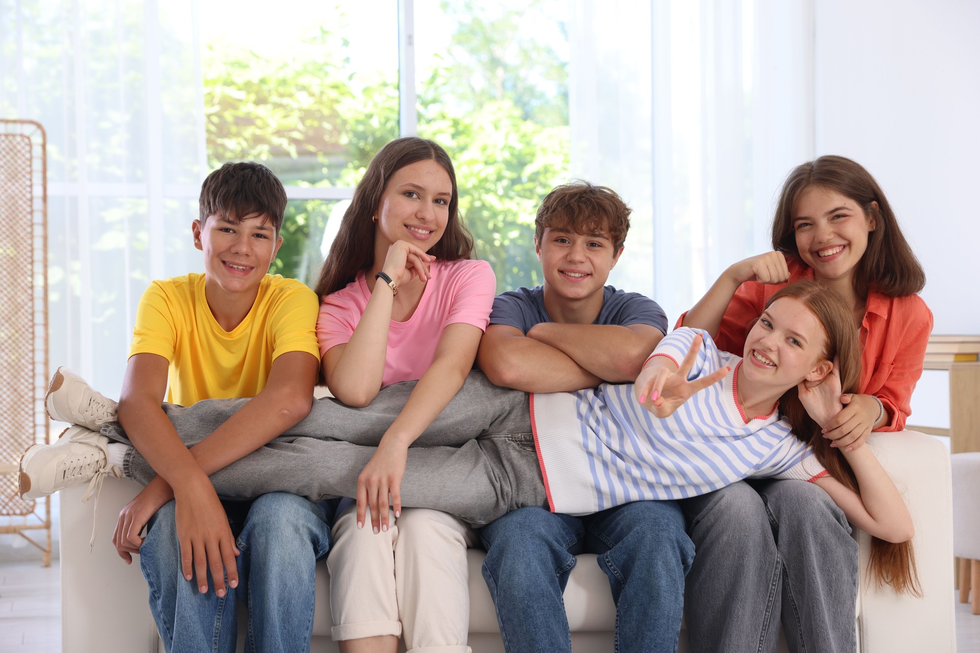 Happy teenage friends sitting on sofa indoors